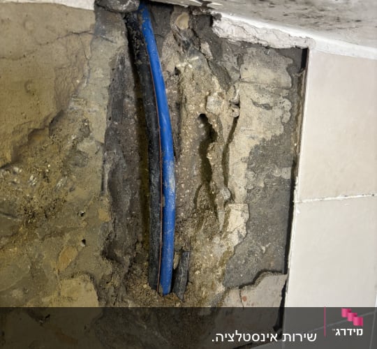 צינור כחול בקיר עם טיח מתקלף